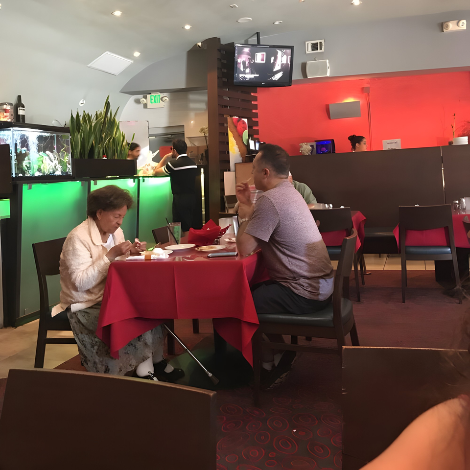 Diners at Farsi Cafe, with an older woman and man seated at a red-clothed table.