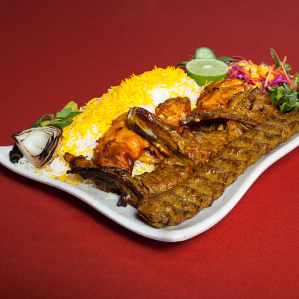 Farsi Cafe's Persian platter with various kebabs, saffron rice, grilled onion, and salad on a white plate.